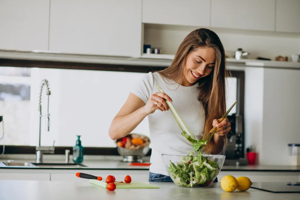 young-woman-making-salad-at-the-kitchen.jpg
